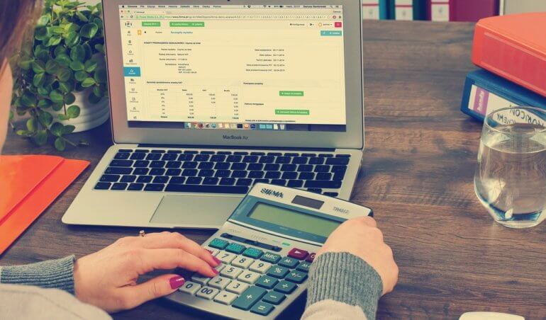 pessoa com calculadora e computador para realizar a contabilidade de condomínio