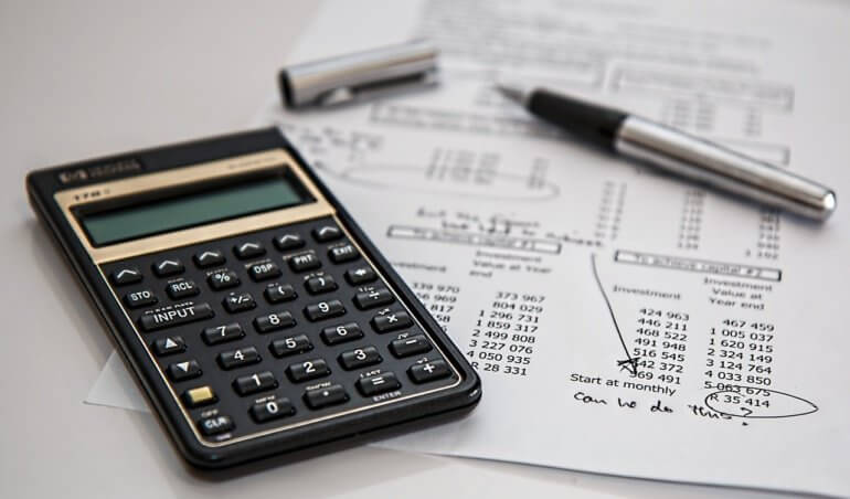 calculadora, caneta e relatório para calcular a taxa de condomínio